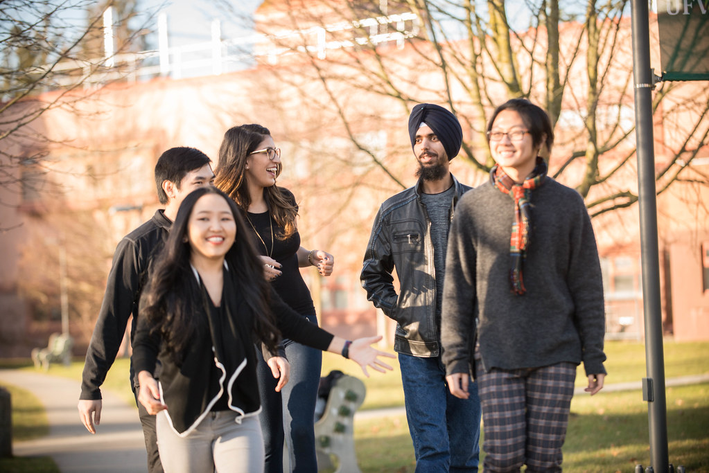 international student image: a group of diverse students walk on a college campus
