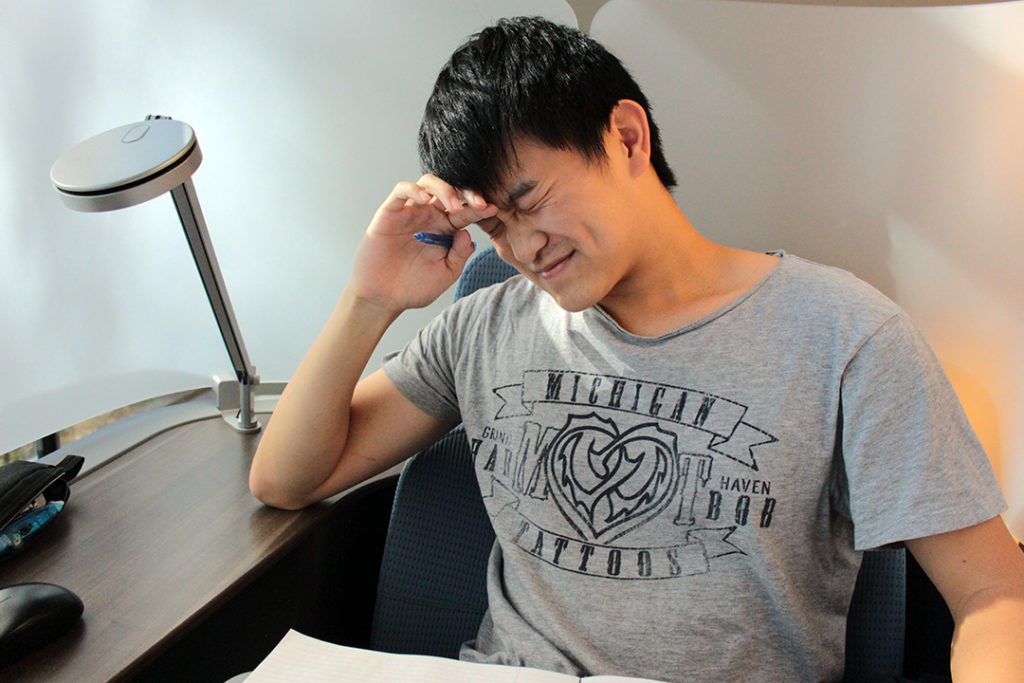 self care during the college application process image: collegeadvisor.com; a stressed BIPOC student rubs forehead with eyes tightly closed