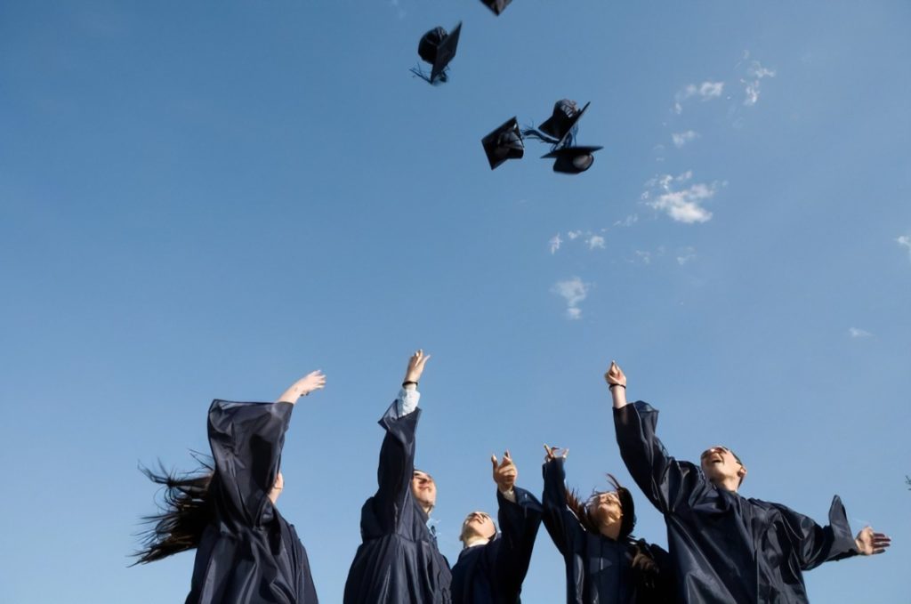 Dream school; collegeadvisor.com image: a photo of four students tossing graduation caps in the air.